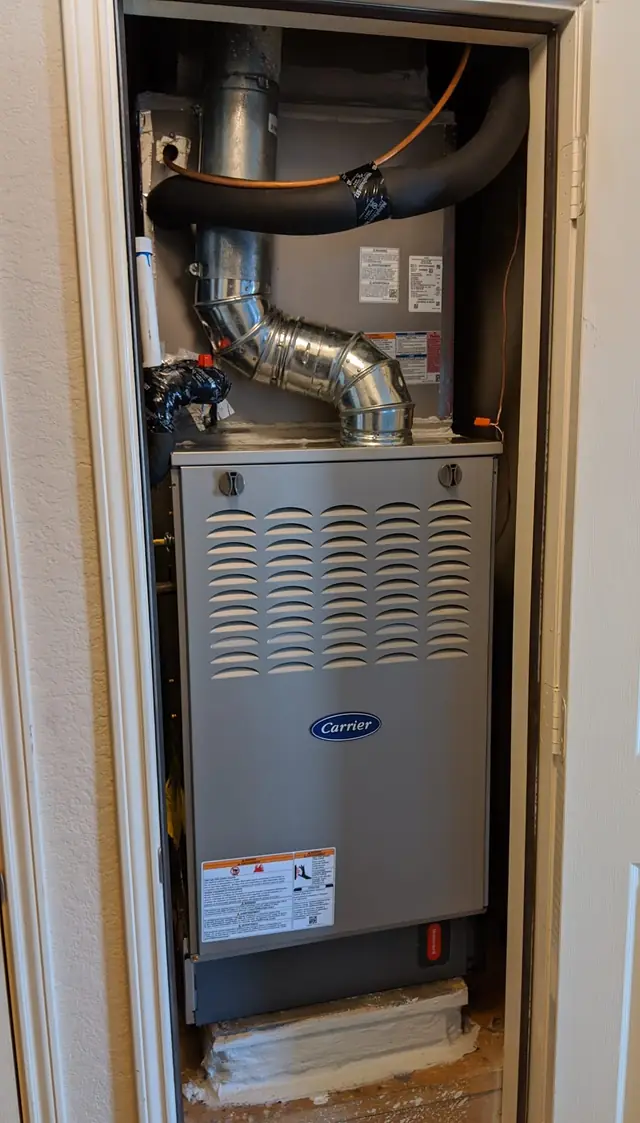 A Carrier gas furnace installed in an interior closet with the flue and line set dressed in