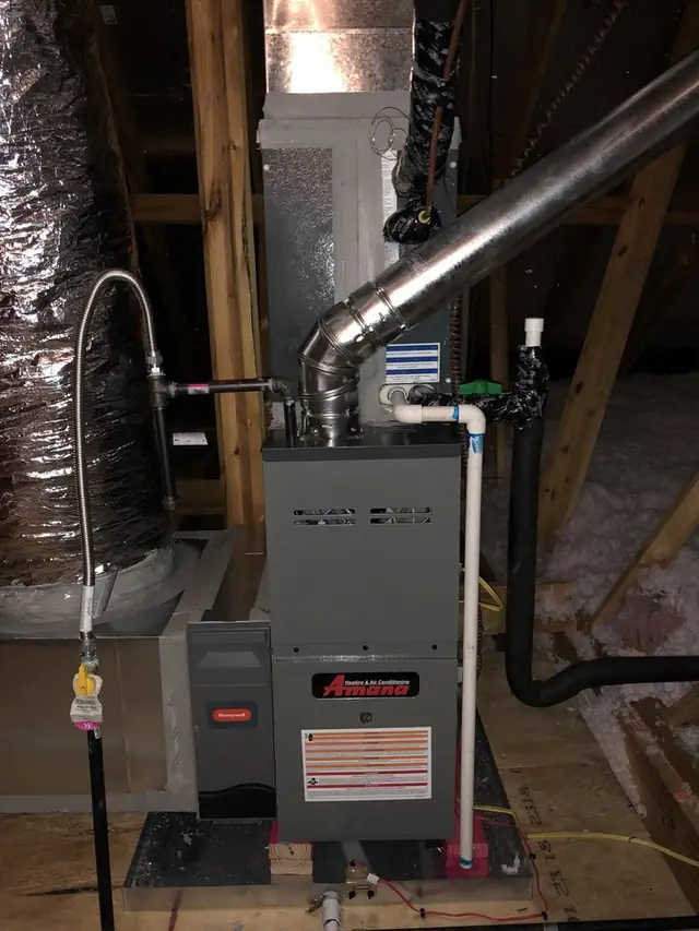 A gas furnace installed in an attic with its flue, condensate drain and gas line run