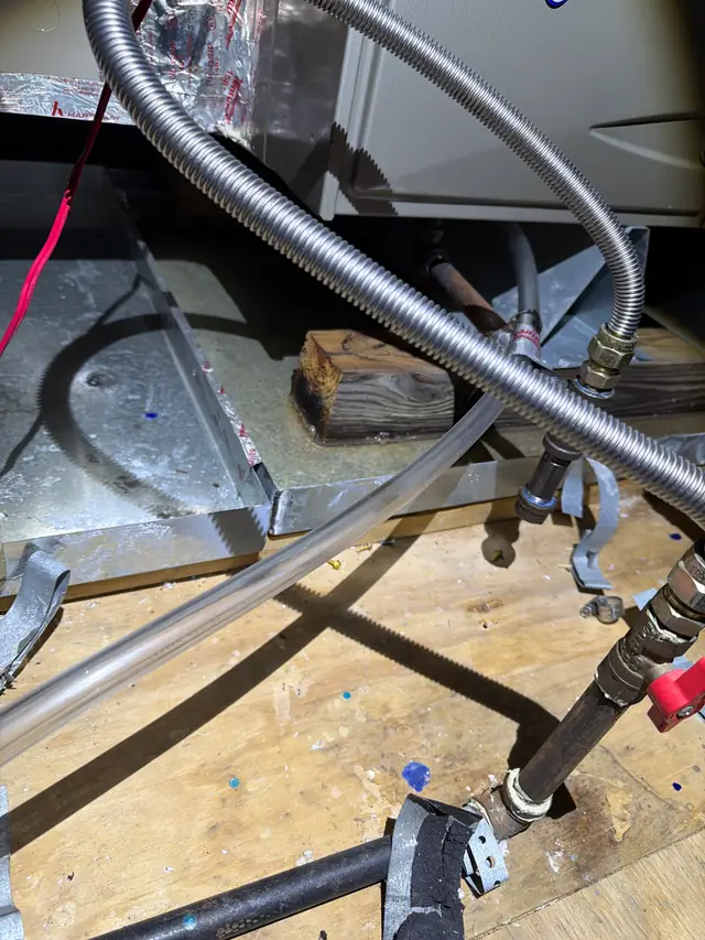 Drain lines and a flex connector beneath an indoor air handler on an attic platform