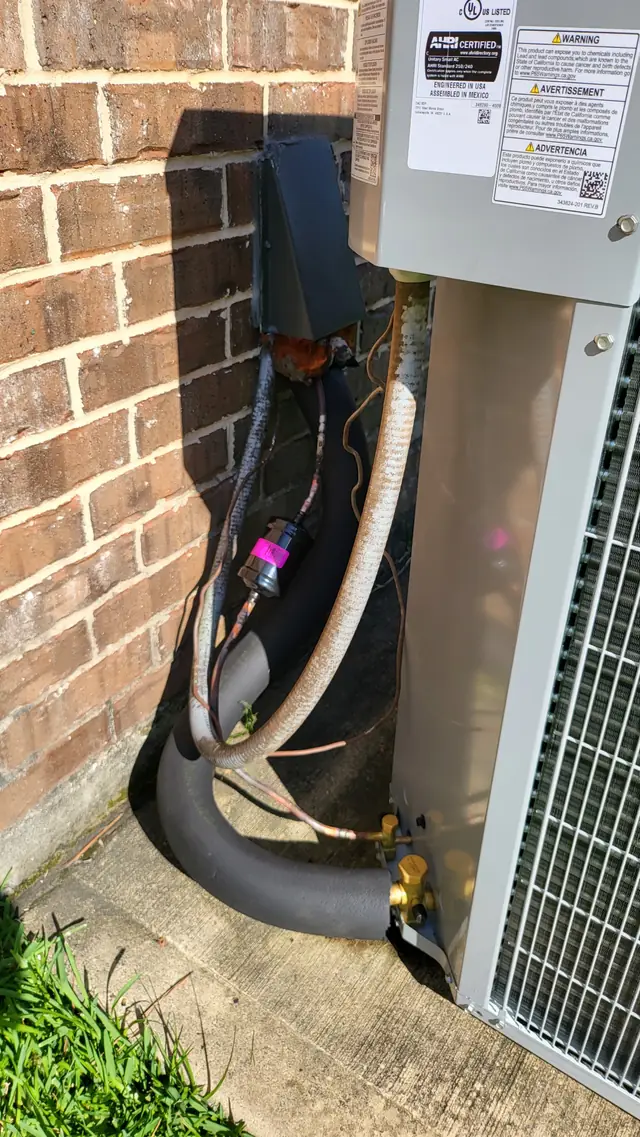 Refrigerant line set, disconnect box and service valves at the base of an outdoor unit against brick